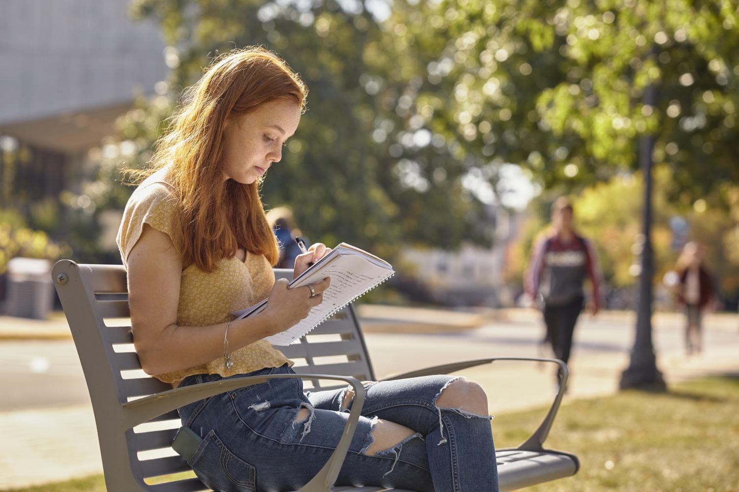 A <a href='http://oezzuk.azarnewsonline.com'>全球十大赌钱排行app</a> student reads on a bench along Campus Drive.